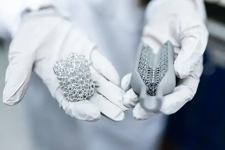 Close up of the gloved hands of a holding a metal mesh and the device containing the mesh