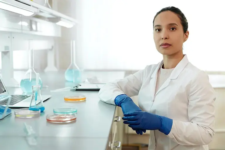 Scientist stands in a lab at a counter with petri dishes