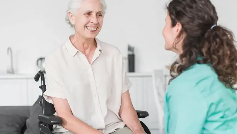 Healthcare professional holding hands with an older woman in a wheelchair