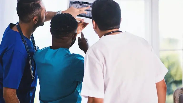 Rear view of three healthcare professionals examining a medical photograph