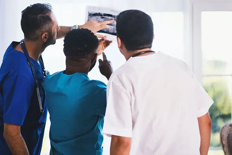 Rear view of three healthcare professionals examining a medical photograph