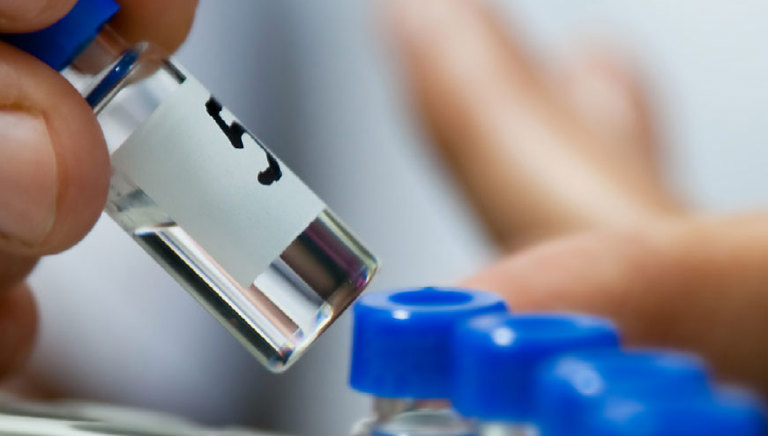 Close up a filled medicine vial being picked up