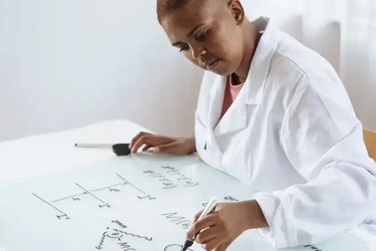 Scientist looking at large sheet on a desk which features mathematical equations