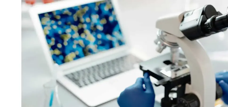 Over the shoulder view of a scientist looking down a microscope