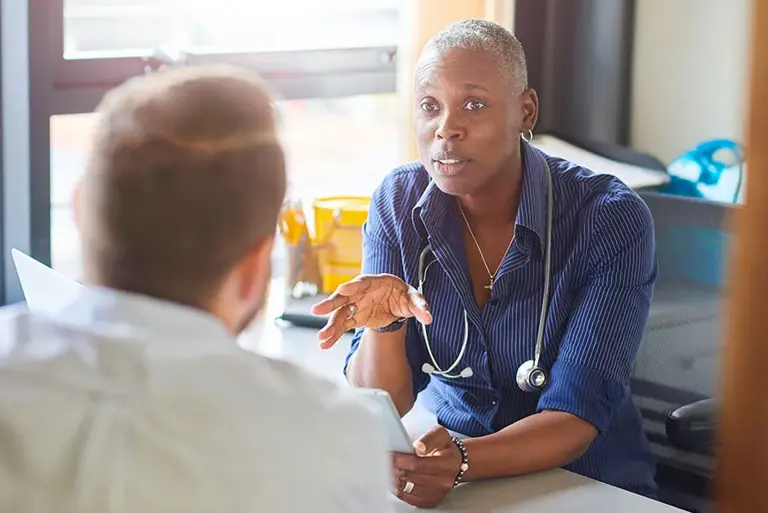 Doctor sat in in their surgery talking with a patient