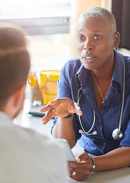 Doctor sat in in their surgery talking with a patient