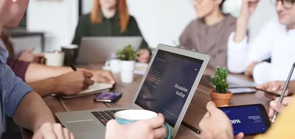 Team of office workers sat around a large conference table having a meeting